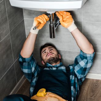 bearded repairman fixing water damage with adjustable wrench in bathroom bearded repairman fixing water damage with adjustable wrench in bathroom